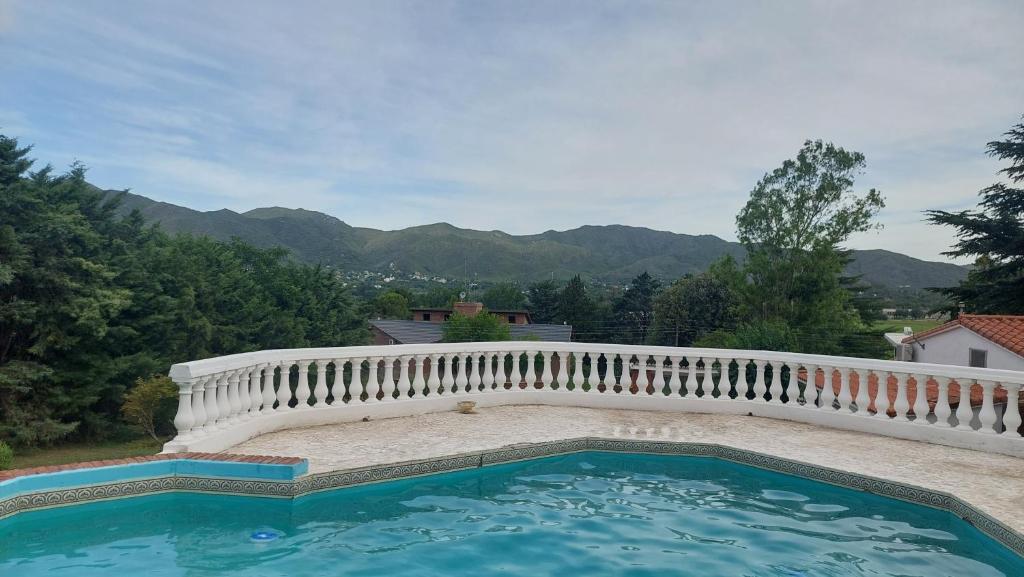 a large swimming pool with a white fence and mountains at Cabaña del mirador in Villa Parque Siquiman