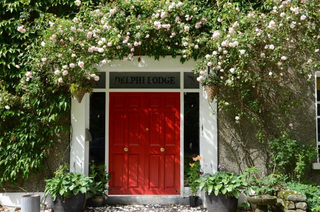 a red door in a building with flowers at Delphi Lodge in Leenaun
