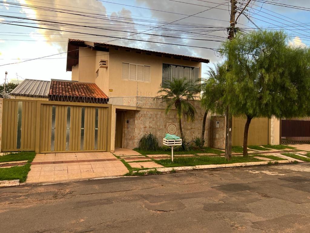 una casa al lado de una calle con un árbol en Quarto privativo em casa domiciliar en Campo Grande