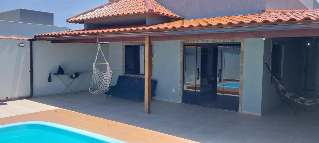 un patio con una hamaca y una piscina en Casa de Temporada no Paraíso de Arraial do Cabo en Arraial do Cabo