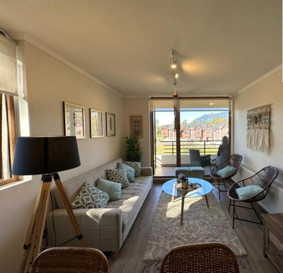 un soggiorno con un divano e un tavolo di CONDOMINIO LOS CASTAÑOS ALICURA, PUCÓN, departamento 2 dormitorios, 1 baño, estacionamiento, piscina a Pucón