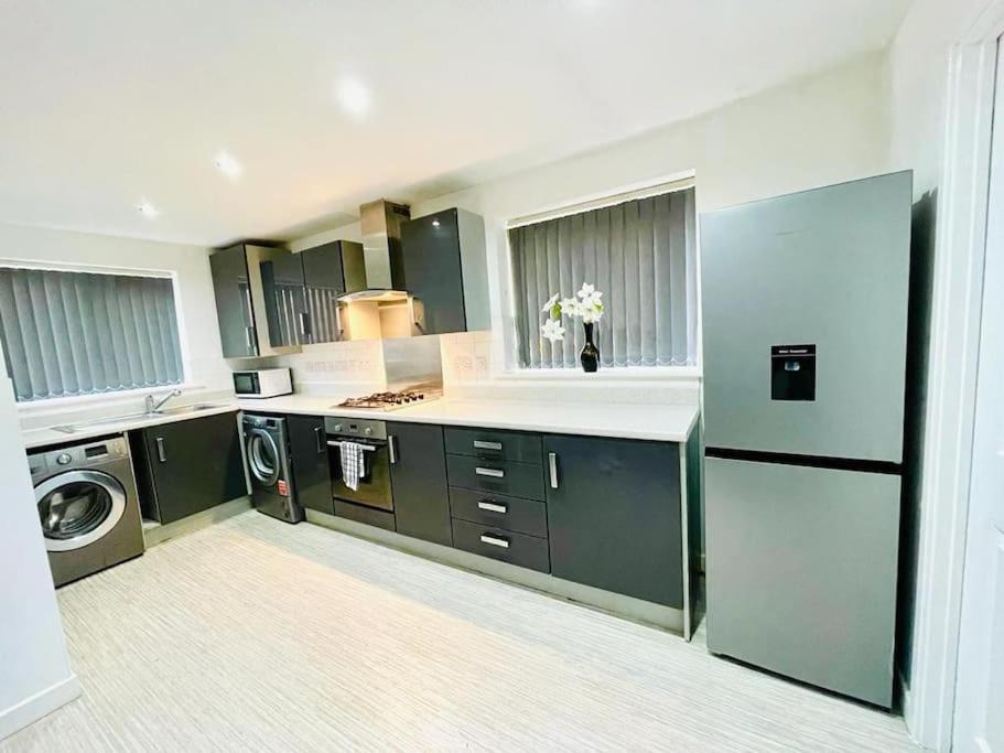 a large kitchen with green cabinets and a appliance at 3 Bedroom Affordable Family Detached House - Business Contractors, Midlands Location - Private garden,Free car park,TV- Netflix and Free WiFi in Coventry