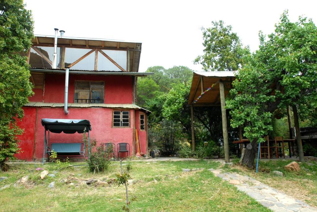 une maison rouge avec un auvent noir dans une cour dans l'établissement Casa en el campo en Quebrada Alvarado, à Olmué