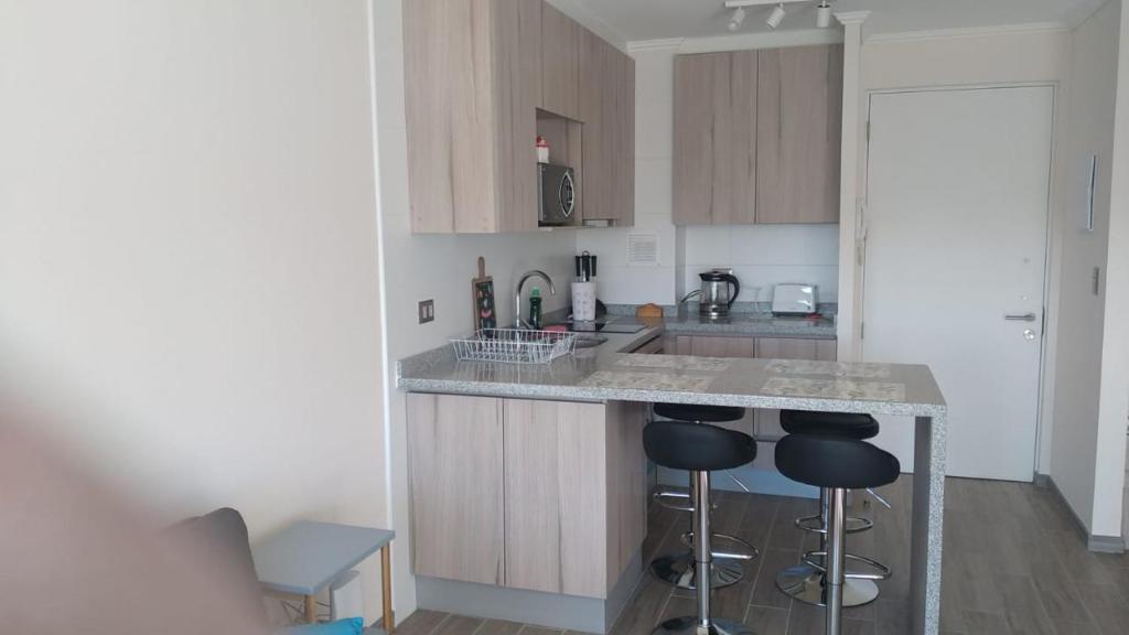 a kitchen with a counter and two bar stools at Departamento Pucon Condominio Alicura in Pucón
