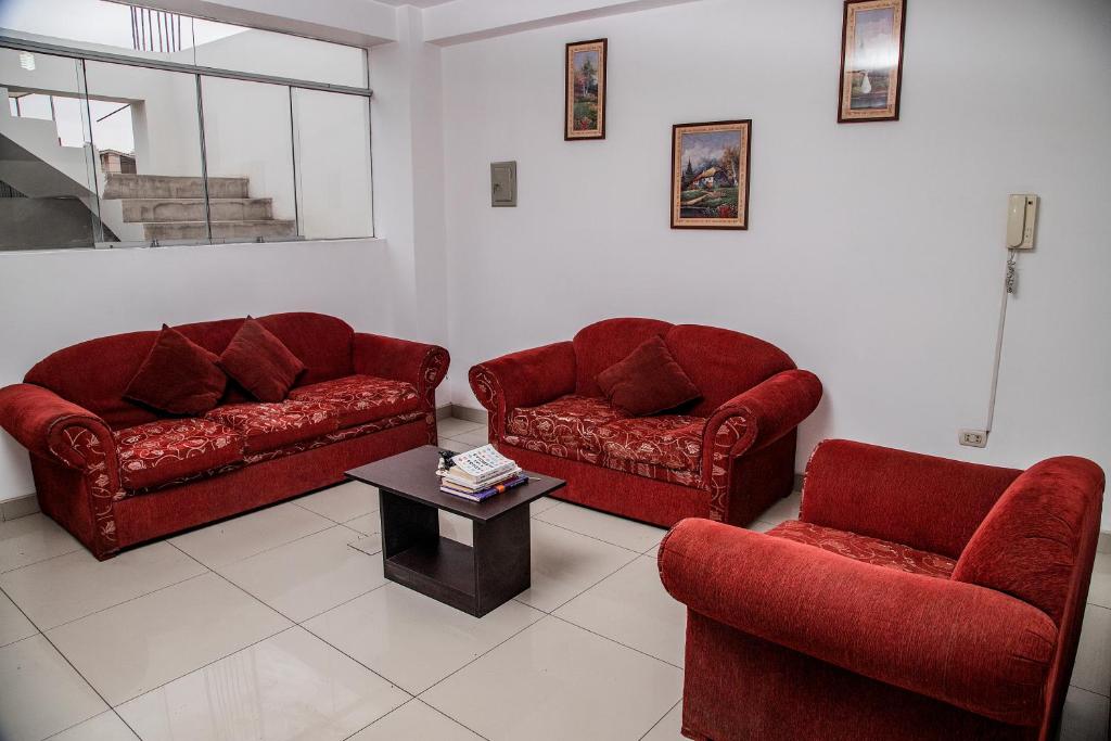 a living room with two red chairs and a table at Lujoso Departamento ,Iluminado , 5 minutos Centro in Tacna