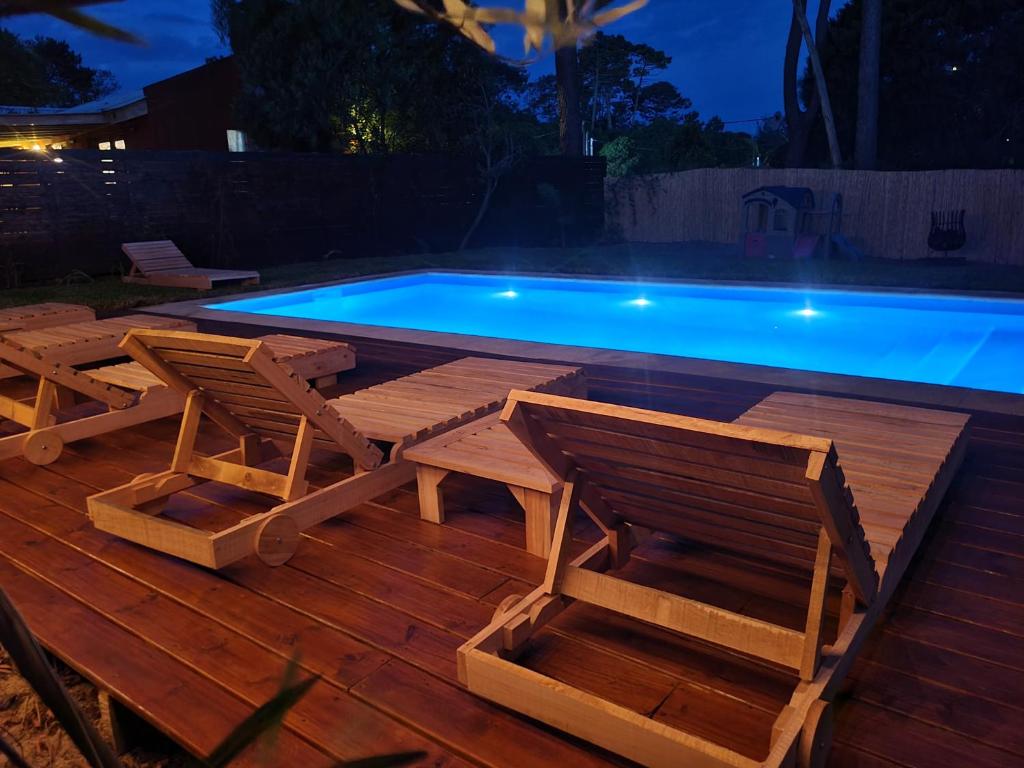 una piscina con 2 sillas de madera, una mesa y una mesa en La Fortunata, en Maldonado