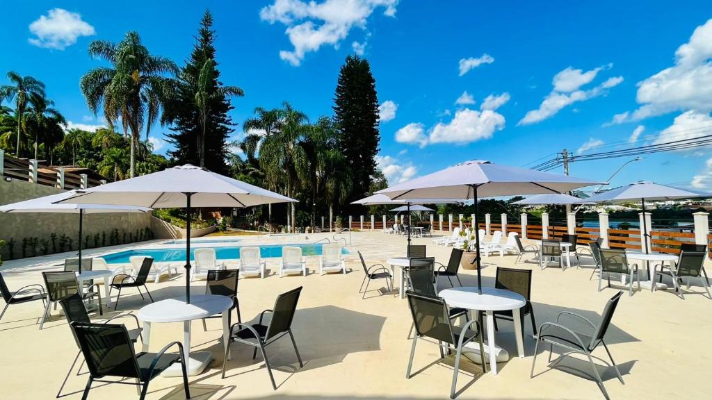 a group of tables and chairs with umbrellas next to a pool at Hotel Varandas do Sol in Poços de Caldas