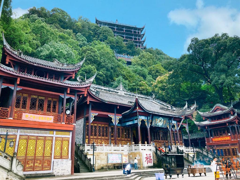 un edificio asiatico con una montagna sullo sfondo di Wuyu Hotel Chongqing Zoo & Yangjiaping The Mixc Light rail a Chongqing
