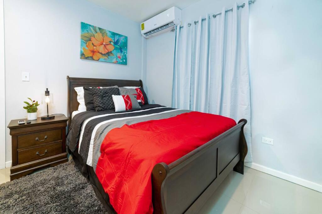 1 dormitorio con 1 cama con manta roja y ventana en Hibiscus Cottage (Mercy's Place) en Buckleys