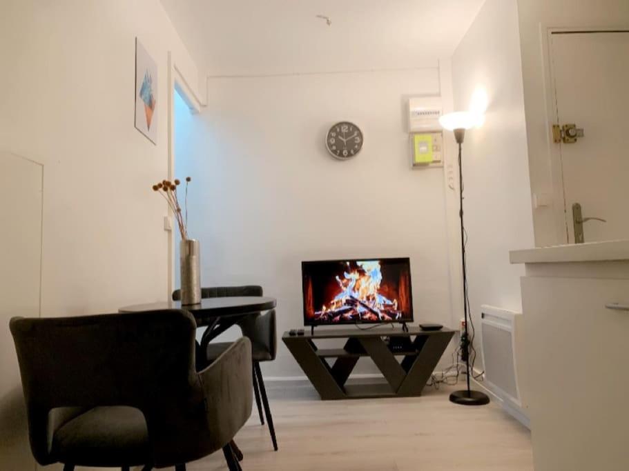 un salon avec une chaise et une télévision sur une table dans l'établissement Coquet Appartement 2 pièces, à Alfortville