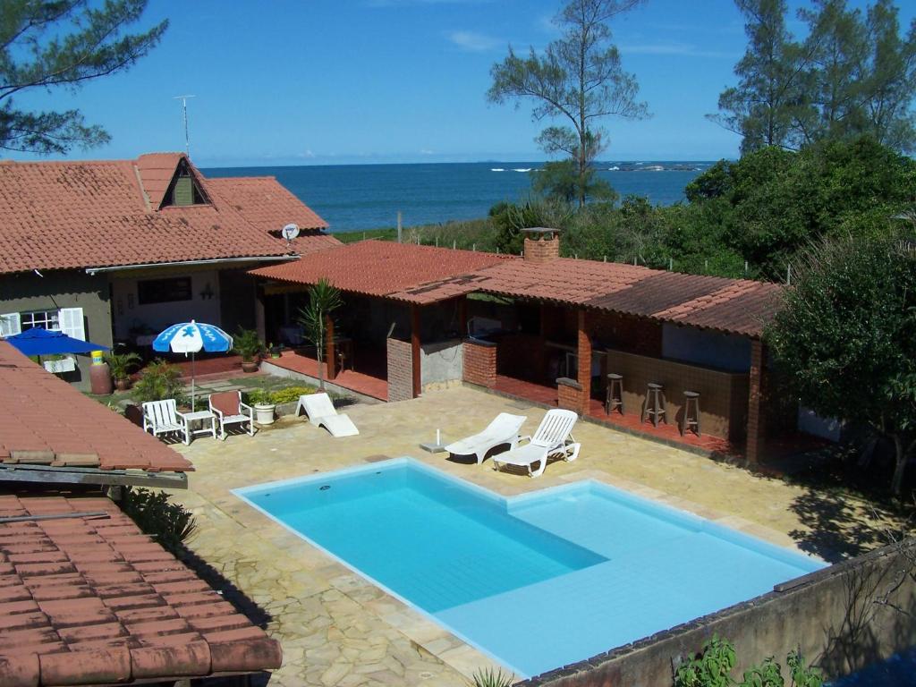 eine Villa mit einem Pool vor einem Haus in der Unterkunft Casa de seis suites na beira do mar in Rio das Ostras