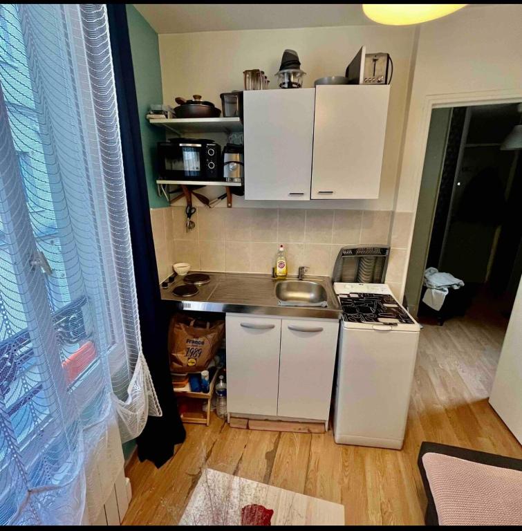 a small kitchen with white cabinets and a sink at Private room in Paris