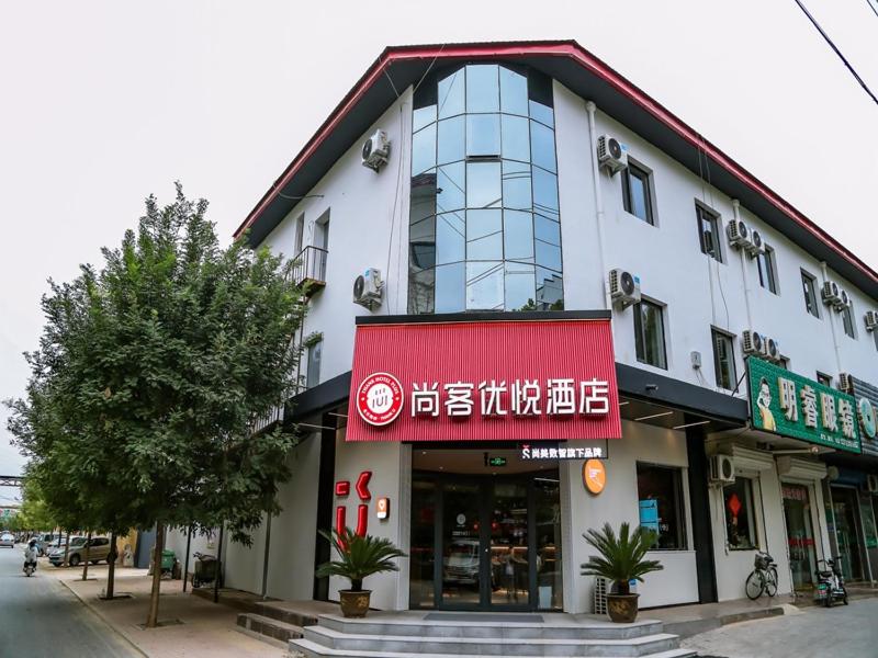 HengshuiにあるThank Inn Chain Hotel Hebei hengshui wuqiang zhenxing roadの赤い看板が目の前にある建物