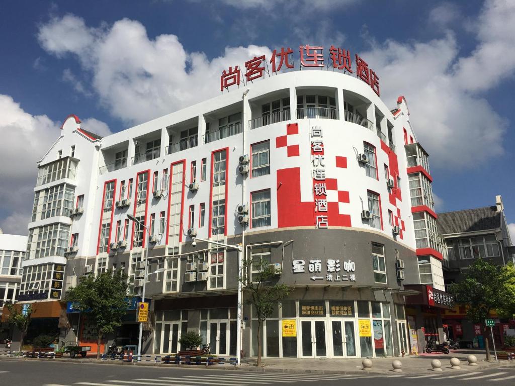 ein großes weißes und rotes Gebäude in einer Stadtstraße in der Unterkunft Thank Inn Chain Hotel Jiangsu Changshu Meili Town Meili in Xuxiang