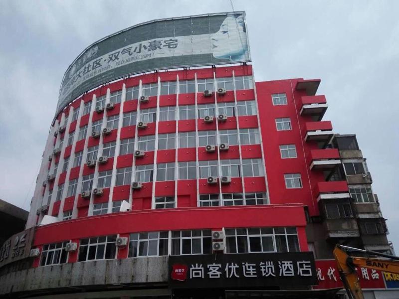 czerwony budynek z napisem na boku w obiekcie Thank Inn Chain Hotel Shangqiu Railway Station West w mieście Shangqiu
