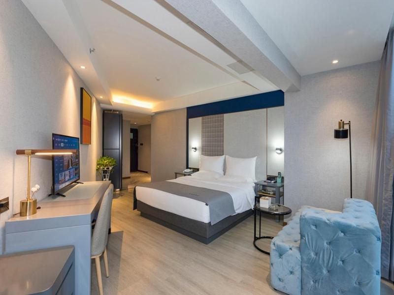 una camera d'albergo con letto e soggiorno di Lano Hotel Guiyang High Speed Rail North Station Dream City a Guiyang