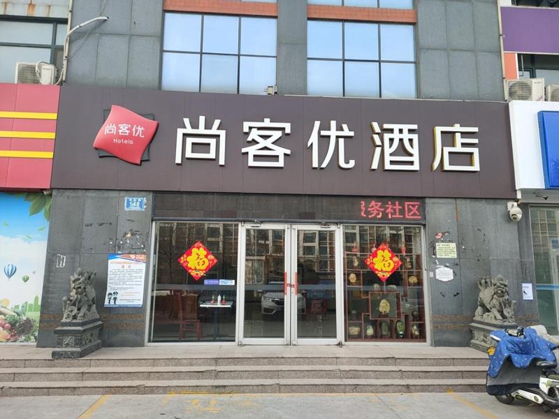 una tienda con carteles en la parte delantera de un edificio en Thank Inn Chain Hotel Shandong Zibo Linzi Heng Haiway, en Xindian