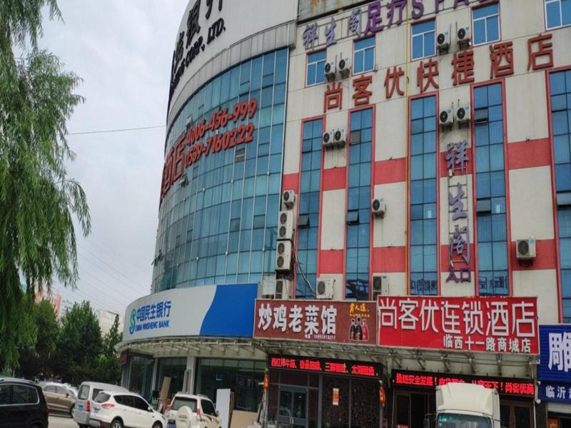 ein großes Gebäude mit seitlichen Schildern in der Unterkunft Thank Inn Chain Hotel West Eleven Road Mall in Linyi