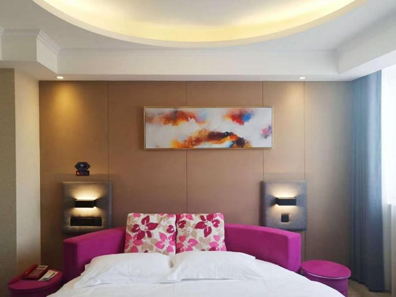 ein Schlafzimmer mit einem lila Bett und einem Gemälde an der Wand in der Unterkunft LanOu Hotel Bengbu Huaishang Wanda Plaza Yiwu Trade City in Bengbu