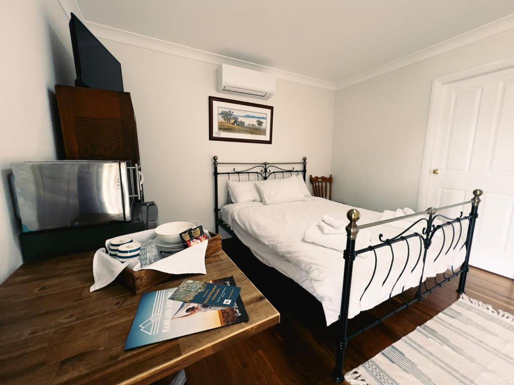 a bedroom with a bed and a table with books at Artshack@Wilgabah in Wallabadah