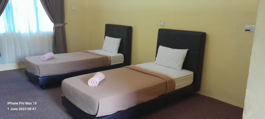 two beds in a hotel room with pink pillows at Alia Tiara River and Beach Resort in Kota Bharu
