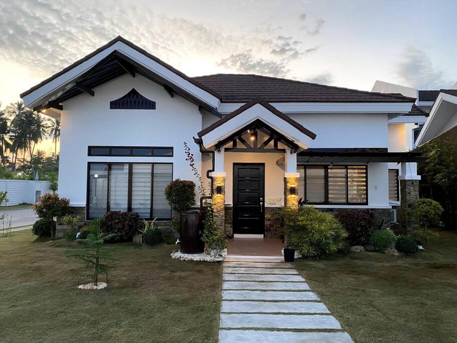 a white house with a black door in a yard at Beach House Retreat in Argao in Argao