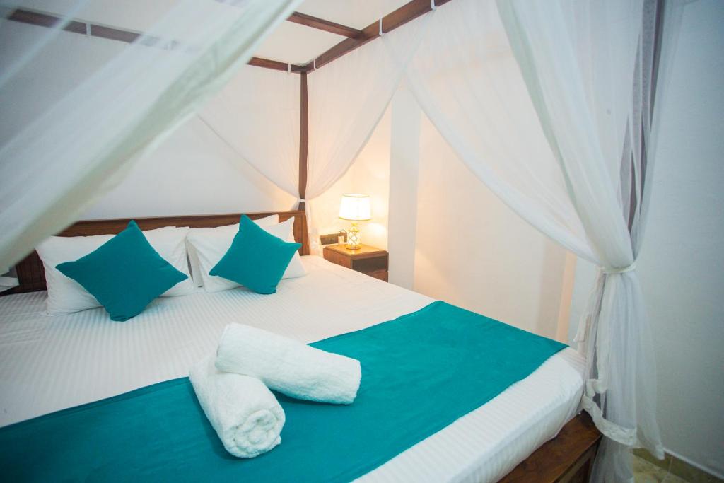 a bedroom with a bed with blue and white pillows at Villa Greenjay Ahangama in Ahangama