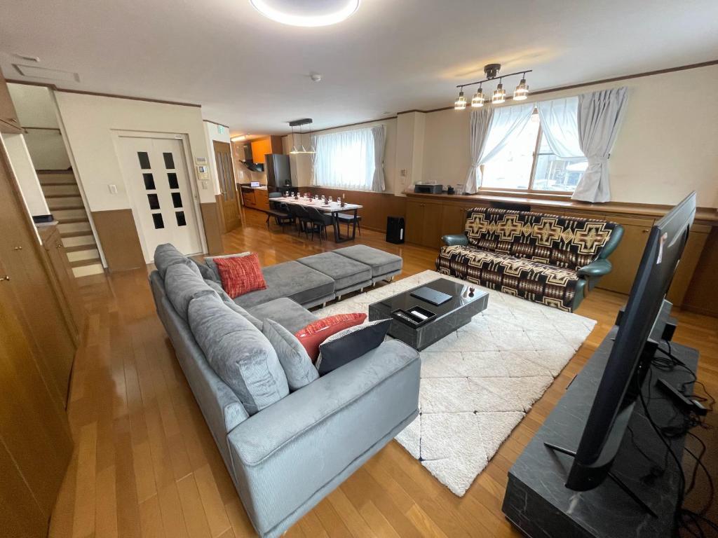 ein Wohnzimmer mit einem Sofa und einem TV in der Unterkunft No1 Private Hotel&Villa Aomoril 186平米貸切 最大12名 in Aomori