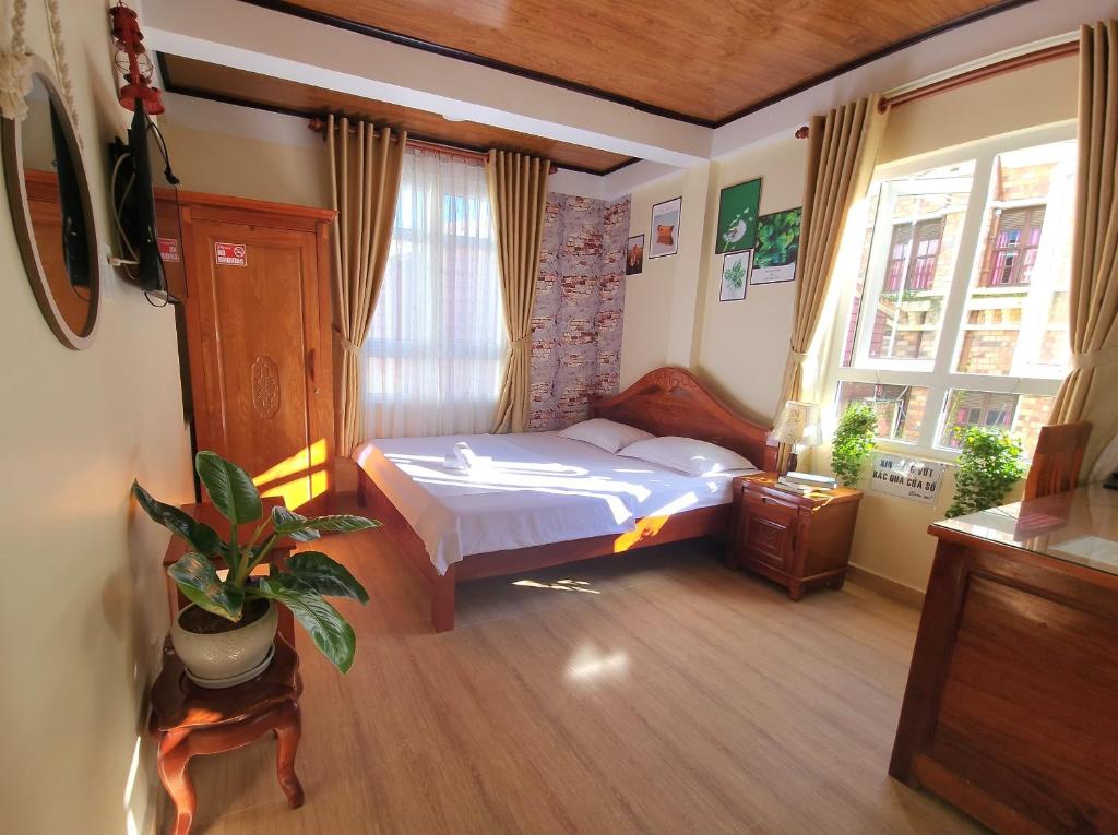 a bedroom with a bed and a potted plant in it at Bình Đào Hotel - Khách sạn ngay trung tâm giá rẻ in Da Lat