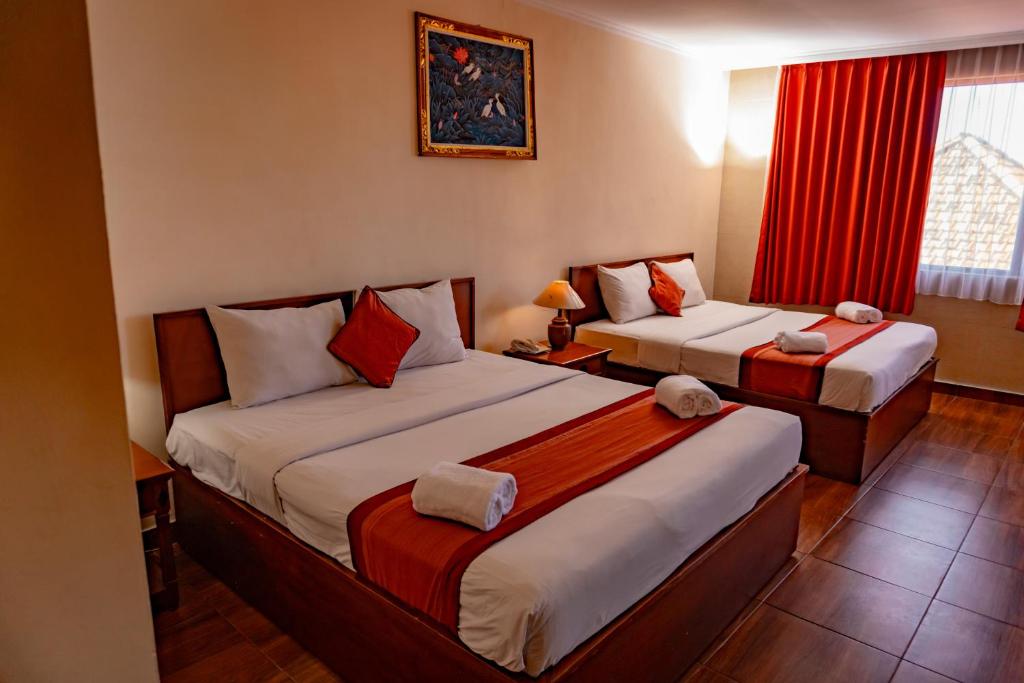 una camera d'albergo con due letti e una finestra di PURI DIBIA HOTEL a Kuta