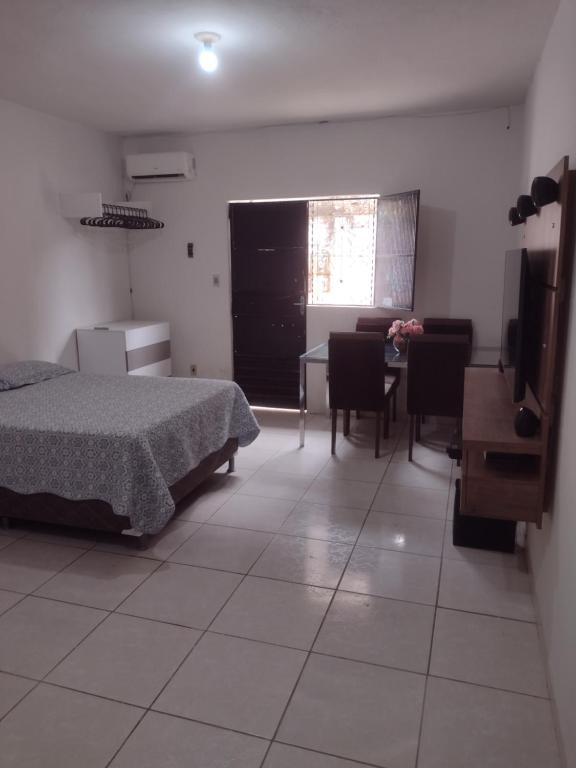 um quarto com uma cama, uma mesa e cadeiras em Conforto simples em Maceió