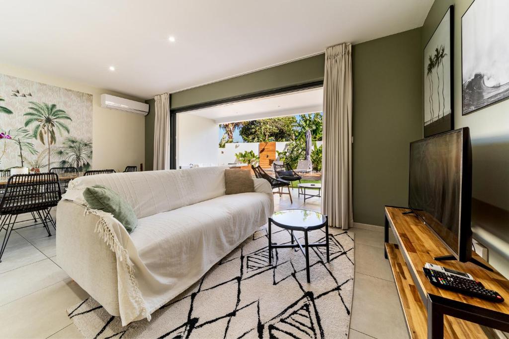 een woonkamer met een bank en een televisie bij Villa moderne Manapany -Jacuzzi-Proximité mer in Saint-Joseph