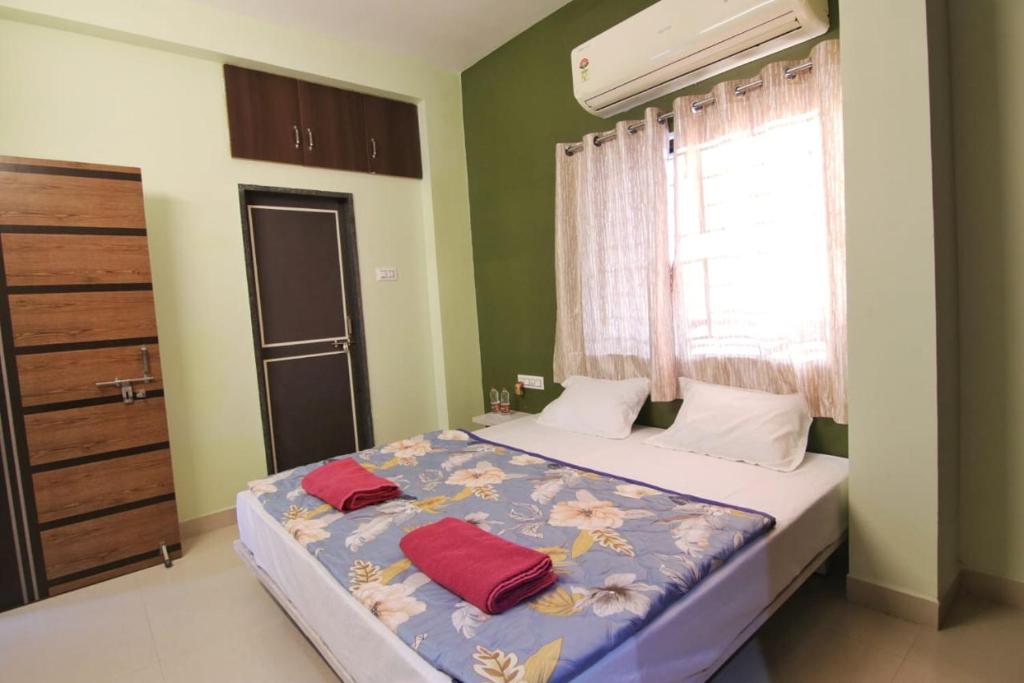 a bedroom with a bed with two red pillows on it at Picaddle Serviced Apartment in Belgaum