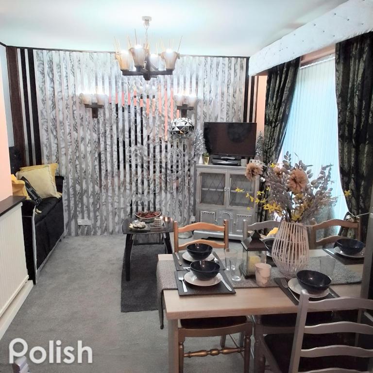 a living room with a table and chairs and a television at Tsalach Short Lets in Nottingham