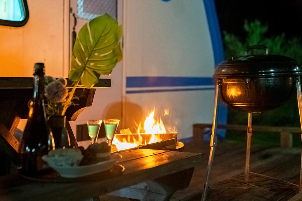 a table with a fire and some bottles and glasses at Gangneung C-cloud caravan in Gangneung