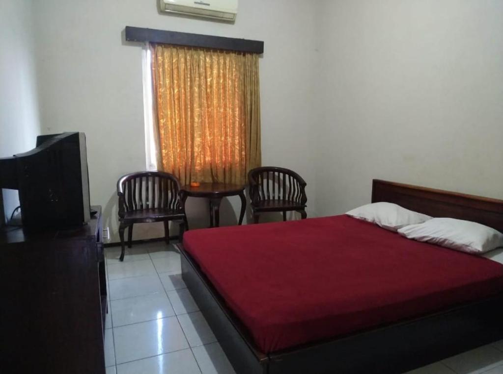 a bedroom with a bed and chairs and a television at Tiara Puspita Laweyan Hotel in Grogol