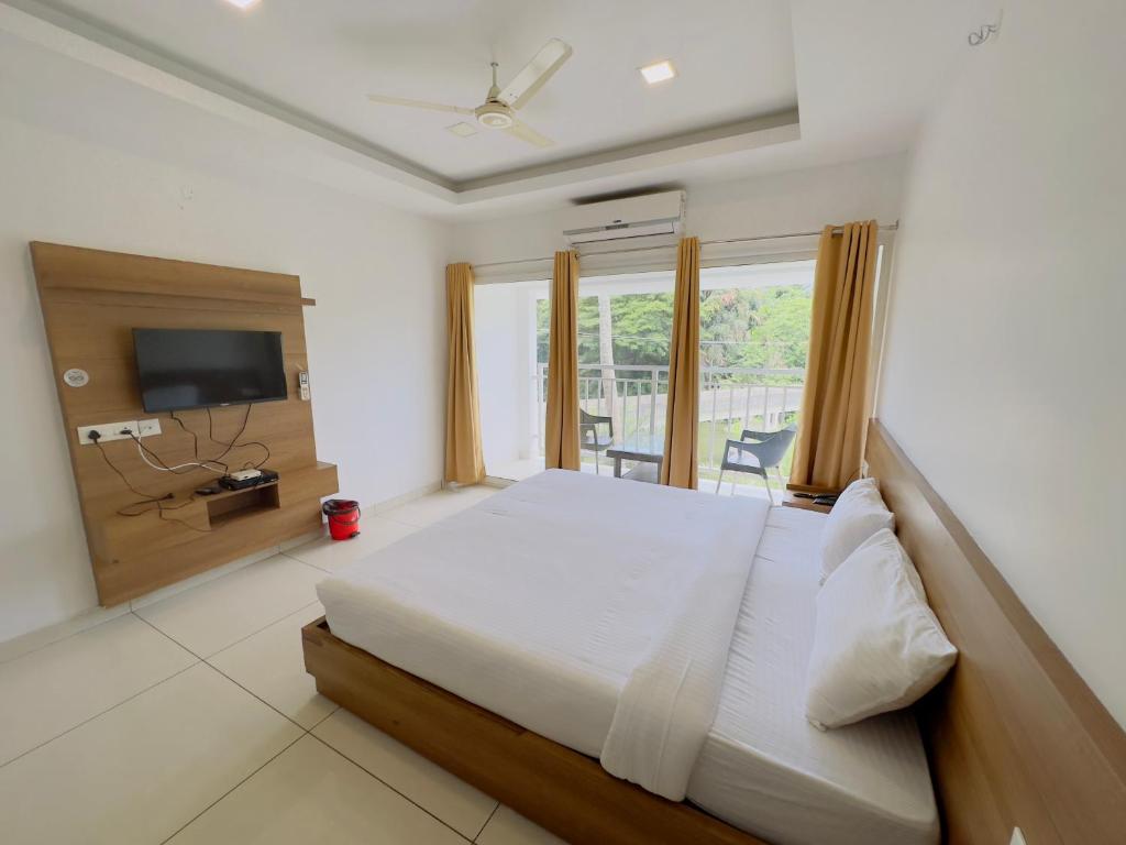 ein Schlafzimmer mit einem großen Bett und einem TV in der Unterkunft HOTEL LETS STAY in Ernakulam