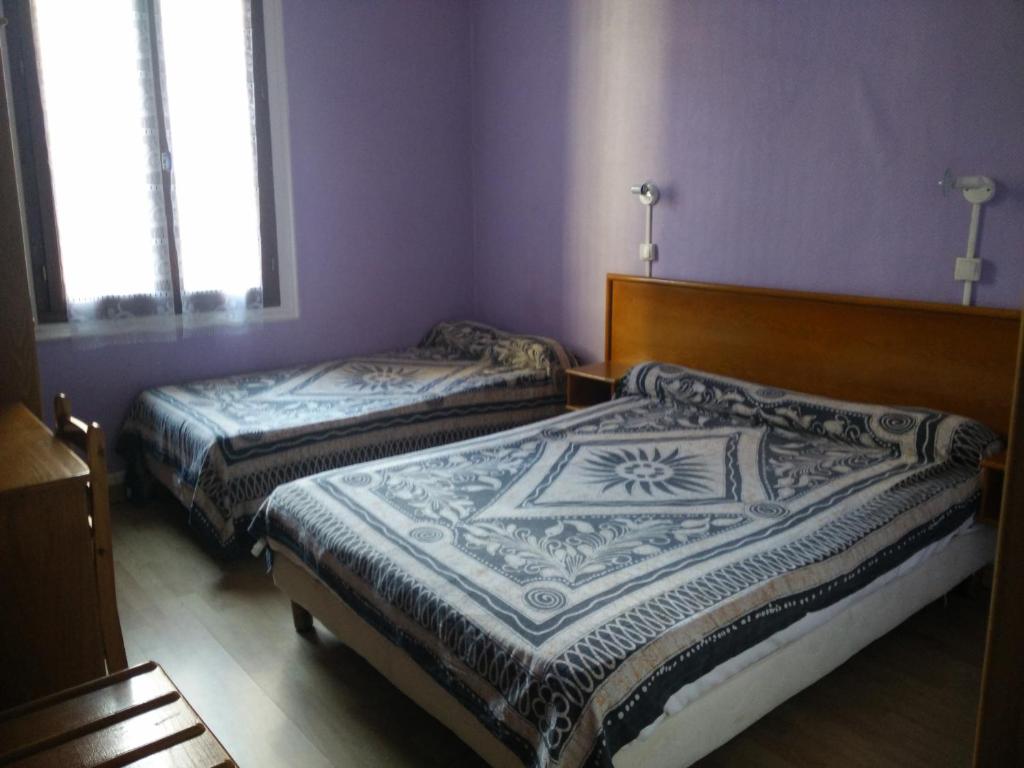 Duas camas num quarto com paredes e janelas roxas em Hotel du Berry em Perpignan