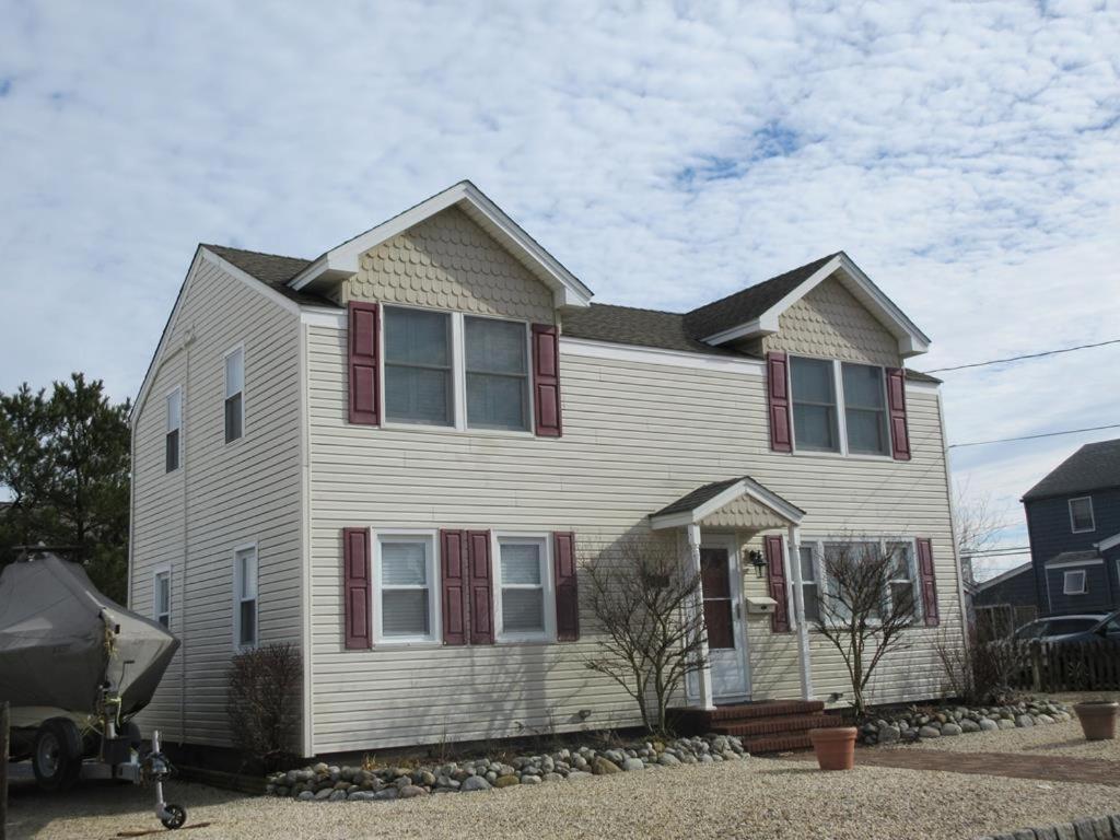 een wit huis met rode luiken bij Haven Beach Oceanside Home - Short Walk To The Beach! in Brant Beach