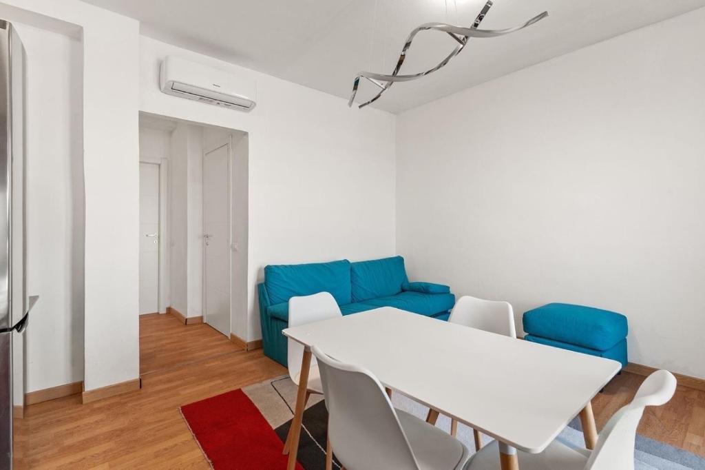 un soggiorno con tavolo bianco e divano blu di Attico & Garage privato a Milano a Cinisello Balsamo