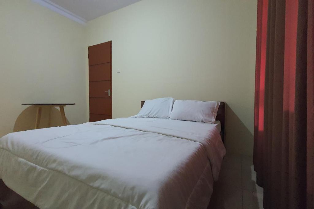 1 dormitorio con cama blanca y mesa en OYO 93523 Penginapan Laras Paminggir, en Rantau