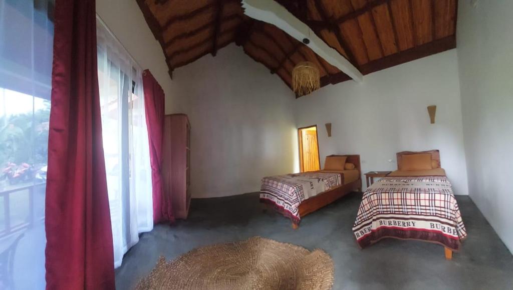 1 dormitorio con 2 camas y ventana en Kambuna Bungalow en Krui