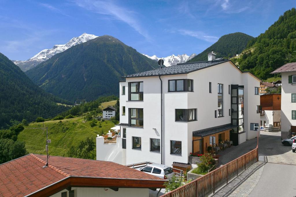 ein weißes Gebäude mit Bergen im Hintergrund in der Unterkunft Hotel Sonne in Stilfs