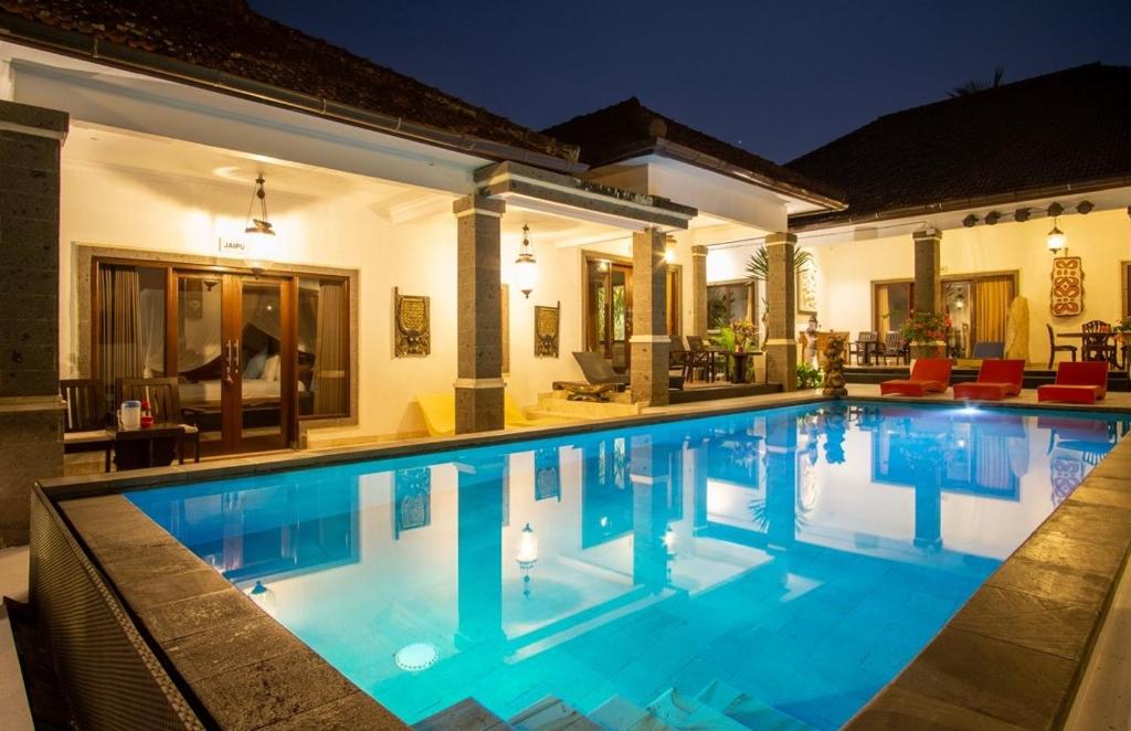 a swimming pool in front of a house at night at Balam Bali Villa in Mengwi