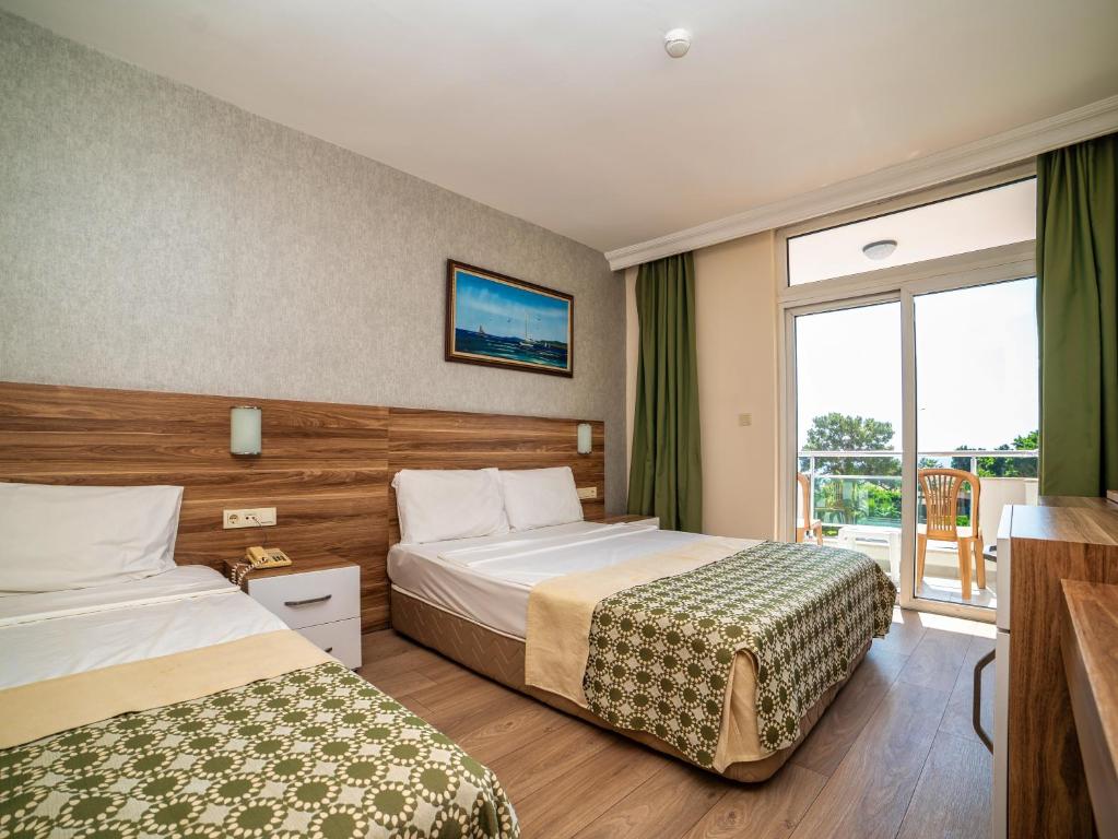 a hotel room with two beds and a balcony at Transatlantik Beach Beldibi in Beldibi