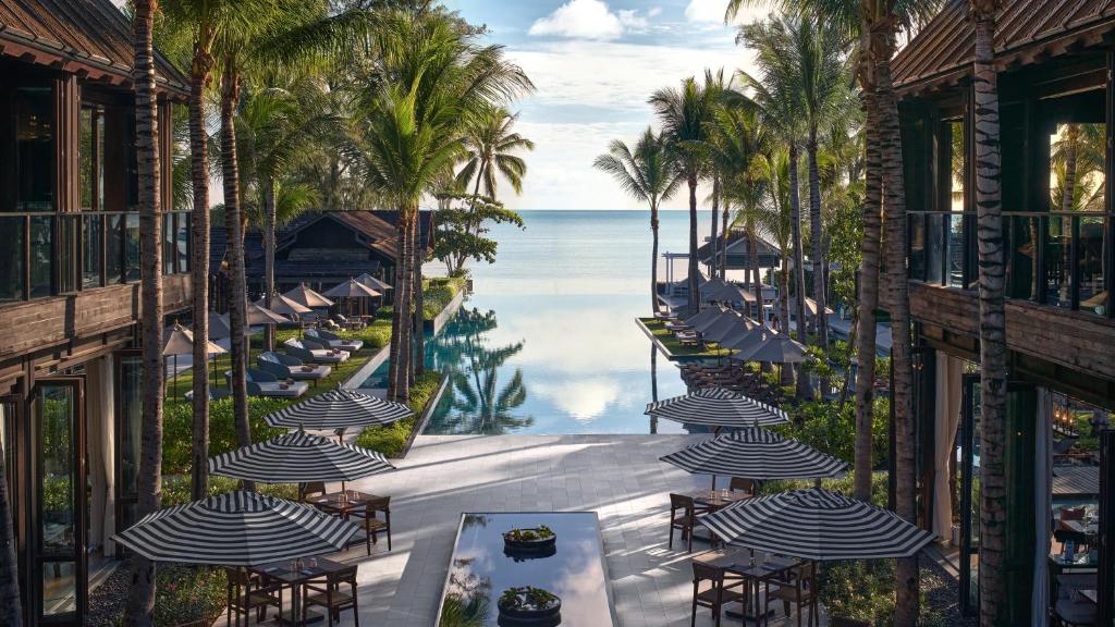 a balcony with tables and umbrellas and the ocean at Kimpton Kitalay Samui, an IHG Hotel in Choeng Mon Beach