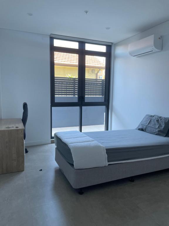 a bedroom with a large bed and a window at Unit 103, 1-5 Oxford Street, Blacktown, NSW 2148 in Blacktown