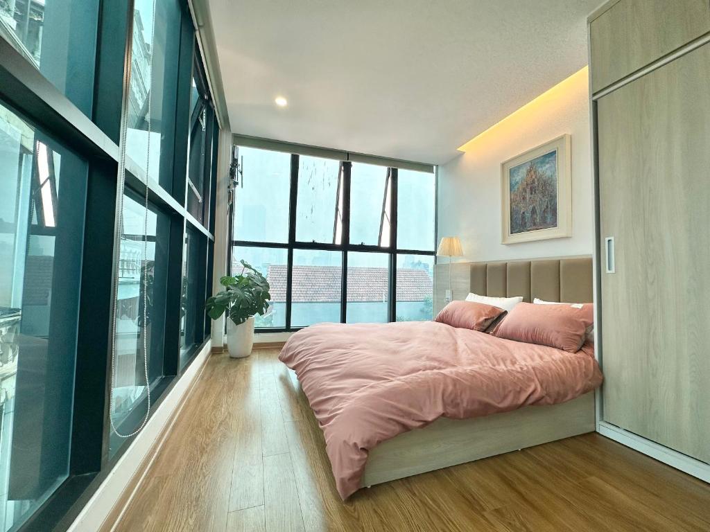 ein Schlafzimmer mit einem großen Bett mit einer rosa Decke in der Unterkunft May Apartment My Dinh Hanoi in Hanoi