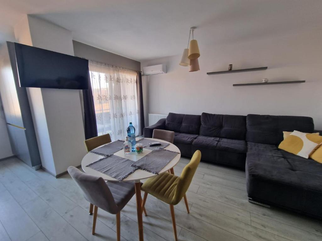 un soggiorno con tavolo e divano di Gray apartment nearby Amethyst & Vivo Mall a Floreşti