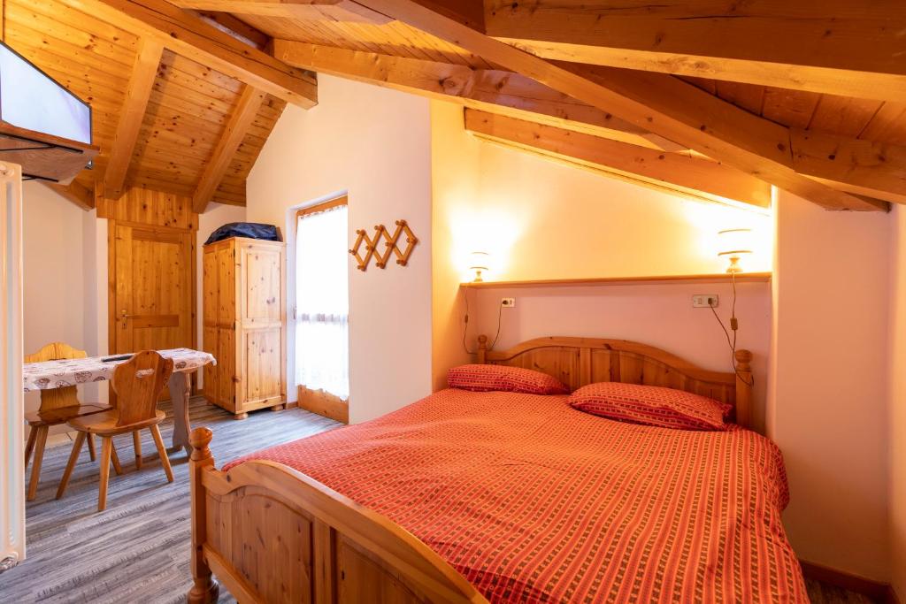 a bedroom with a large bed and a table at Agritur Iellici in Castello di Fiemme